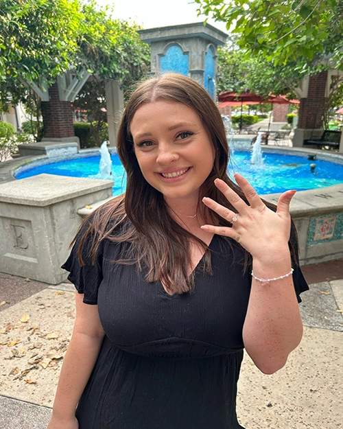 Caryn and Dr. Lawson's oldest child's fiancé stand poolside, showing off her engagement ring.