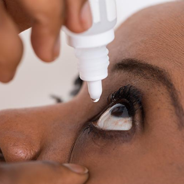 Close up of a woman administering eyedrops.