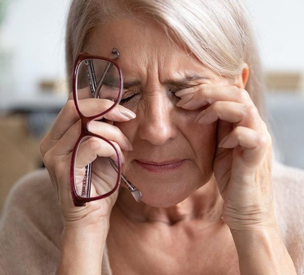 Elderly woman rubs her sore eyes