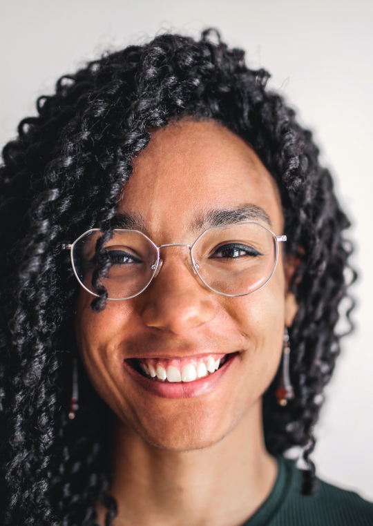 A girl wearing glasses smiles for the camera.