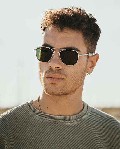 Man with short, curly hair models American Optical sunglasses.