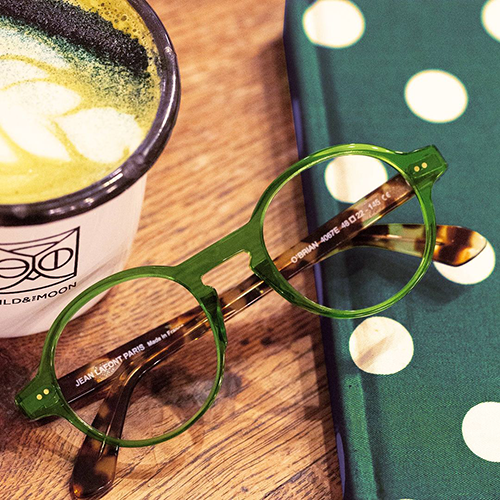 A green pair of Lafont O'Brian glasses sits next to a matcha latte.