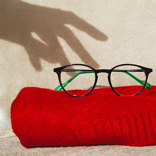 A shadow of a hand reaches for a pair of Lafont Onze glasses sitting on a towel.